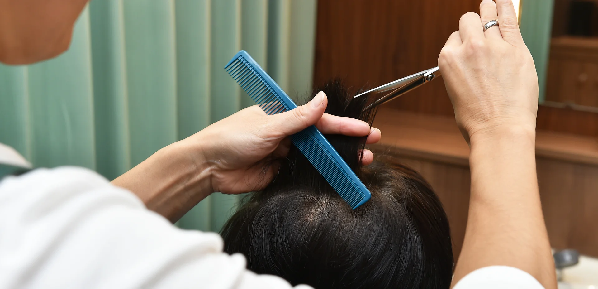 櫛と鋏で髪の長さを整える散髪中の手元