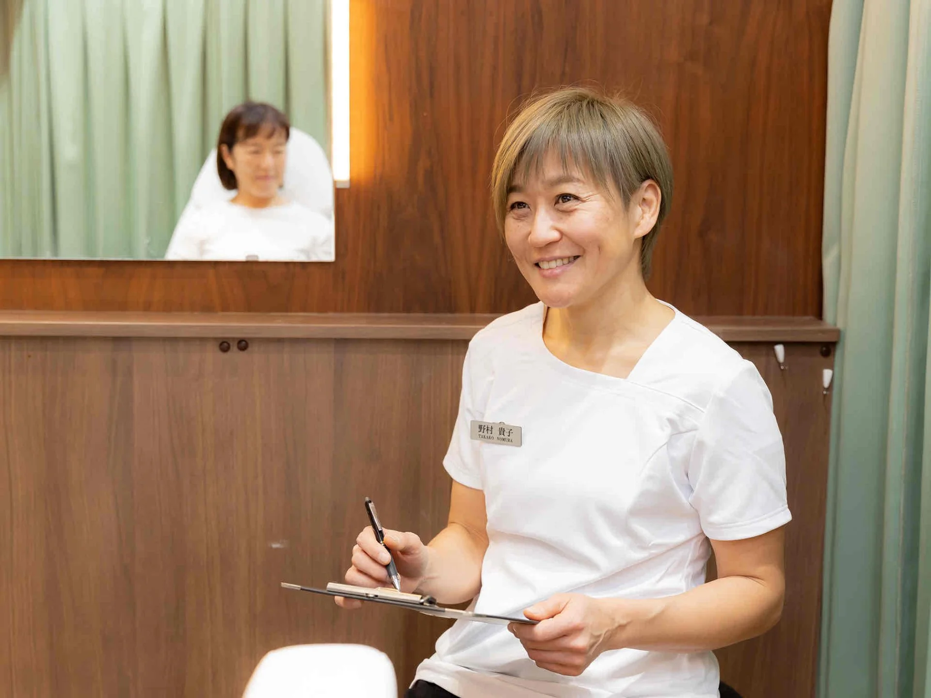 クリップボードを手に微笑む店主の野村貴子